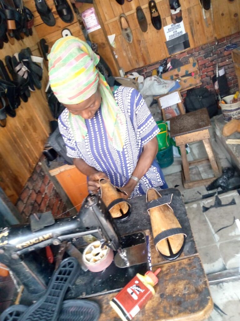 Oluwaseun Florence at her workshop, modeling a pair of sandals.