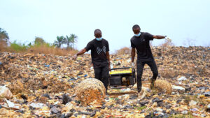 Methane_Munching_Microbes_3 Masters students Chidozie Okafor (left) and Job Aleke (right) carry a generator across a landfill site in Awka, Anambra State