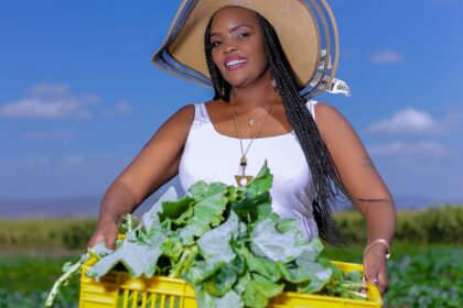 Wangari Kuria holding a crate of vegetables while posing for a picture in Kitengela, Kenya. Photo credit: Wangari Kuria