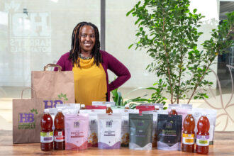 Harriet Chebet posing behind a range of products from Harriet Botanicals in Nairobi, Kenya. Photo credit: Harriet Chebet