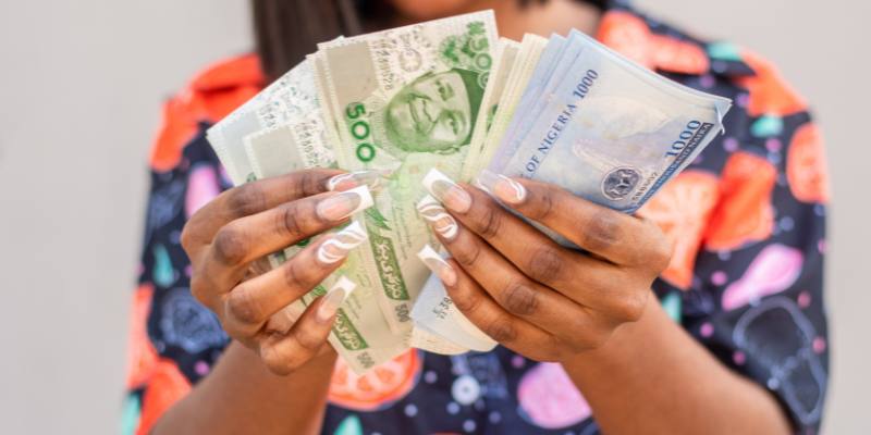 A woman sampling high-currency Naira notes. Photo credit: Piggyvest