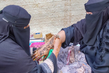 Fatma Hina applying henna on one of her clients in the street of Lamu during the island's cultural festival.