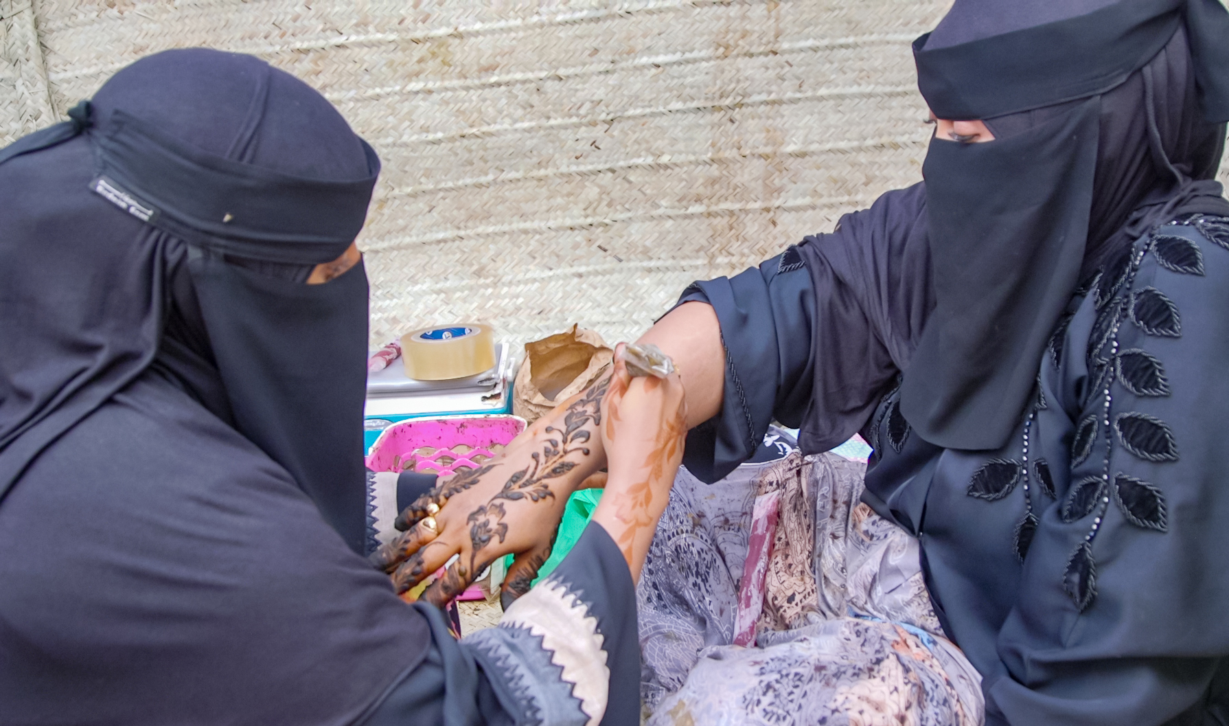 Fatma Hina applying henna on one of her clients in the street of Lamu during the island's cultural festival.