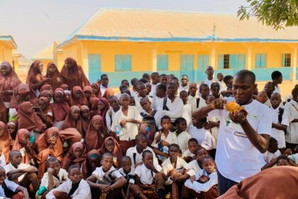 Mohammed demonstrating the process of recycling to a large group of students. Photograph: Sayedi Umar Mohammed