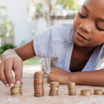 Young african female counting her coins while lying on the floor.