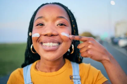 A black woman applying sunscreen to her face. Credit: Yuri Arcurs/Dreamstime.com
