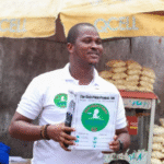 Ishmeal Alfred Charles holds a donation box in Sierra Leone asking passersby to donate money to save a sick child.