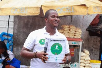 Ishmeal Alfred Charles holds a donation box in Sierra Leone asking passersby to donate money to save a sick child.